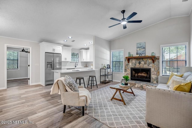 living room featuring baseboards, ornamental molding, light wood-style floors, lofted ceiling, and ceiling fan
