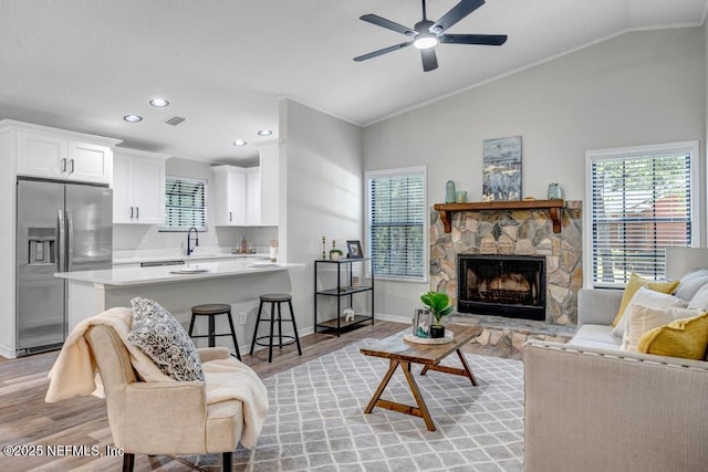 living room with visible vents, ornamental molding, light wood-style floors, and lofted ceiling