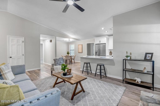 living area featuring baseboards, ceiling fan, light wood-type flooring, recessed lighting, and vaulted ceiling