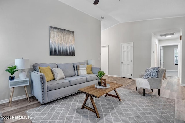 living room featuring visible vents, light wood-type flooring, baseboards, and lofted ceiling