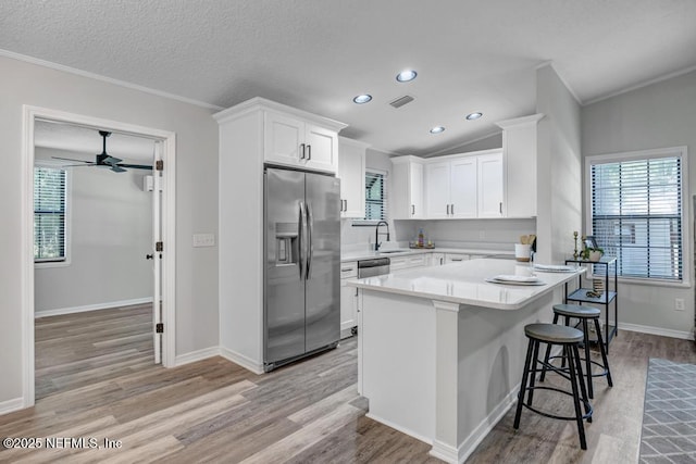 kitchen featuring stainless steel appliances, light wood-style flooring, a sink, and crown molding