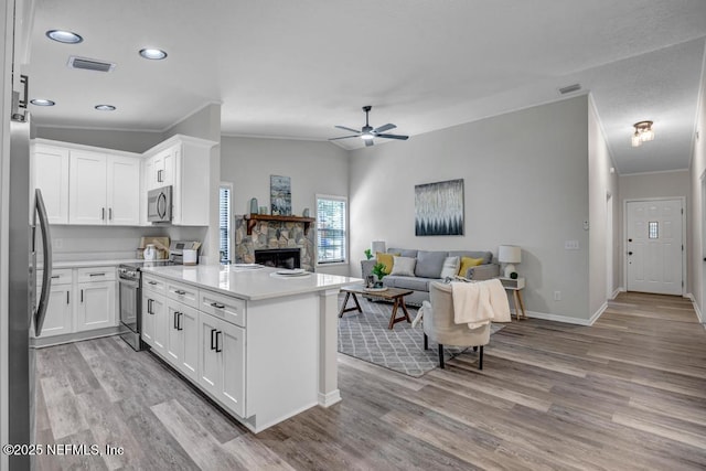 kitchen featuring visible vents, a ceiling fan, a peninsula, crown molding, and stainless steel appliances