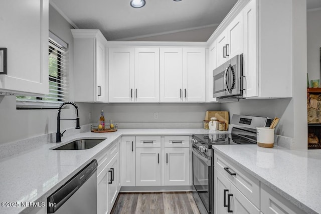 kitchen with crown molding, white cabinets, light stone countertops, appliances with stainless steel finishes, and a sink