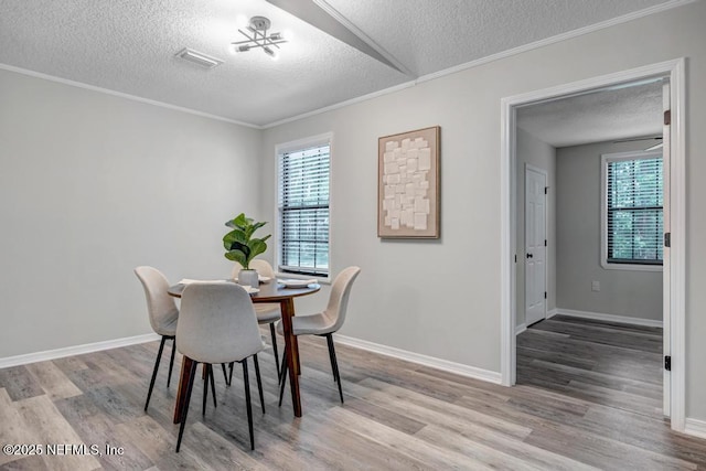 dining space featuring visible vents, light wood-style floors, and a textured ceiling
