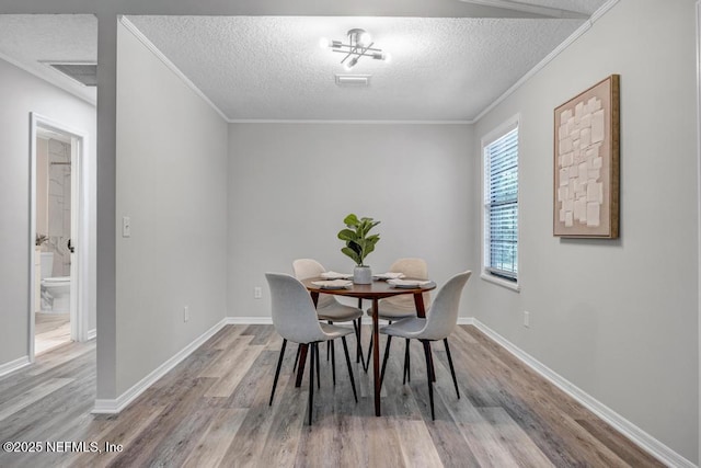 dining area with baseboards, wood finished floors, and a textured ceiling