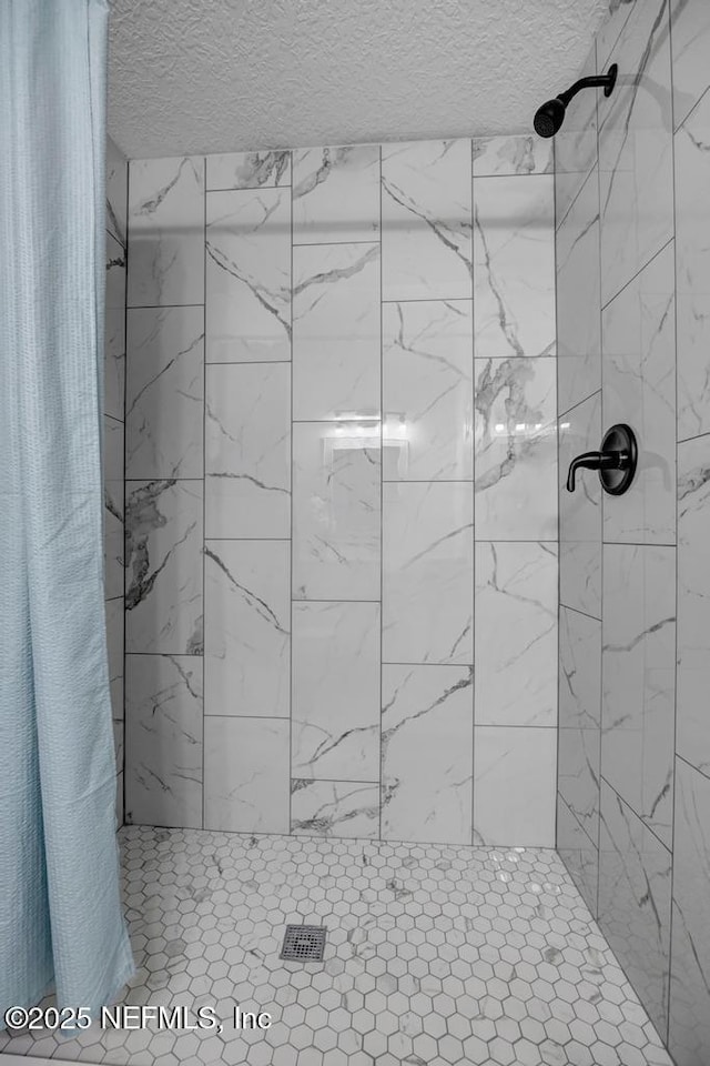 full bath featuring a tile shower and a textured ceiling