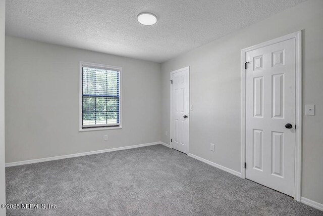 spare room featuring a textured ceiling, carpet flooring, and baseboards