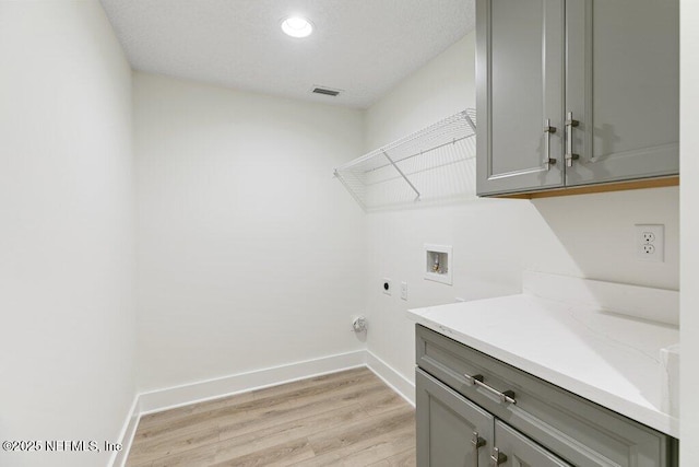 9921 Derby Gate Ct, Jacksonville, FL 32219 - laundry room with hookup for a washing machine, hookup for an electric dryer, light wood-style flooring, cabinet space, and baseboards