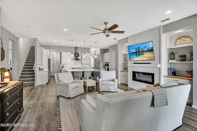 559 Willow Lake Dr, Saint Augustine, FL 32092 - living area featuring visible vents, stairs, ceiling fan, dark wood finished floors, and a glass covered fireplace