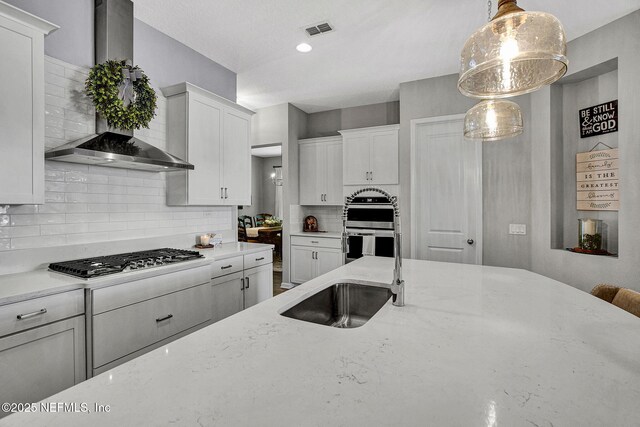 559 Willow Lake Dr, Saint Augustine, FL 32092 - kitchen with white cabinetry, tasteful backsplash, gas cooktop, wall chimney range hood, and visible vents