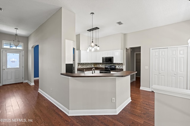 kitchen featuring stainless steel microwave, dark countertops, backsplash, and black / electric stove