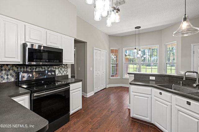 kitchen featuring stainless steel microwave, dark countertops, black range with electric cooktop, and a notable chandelier
