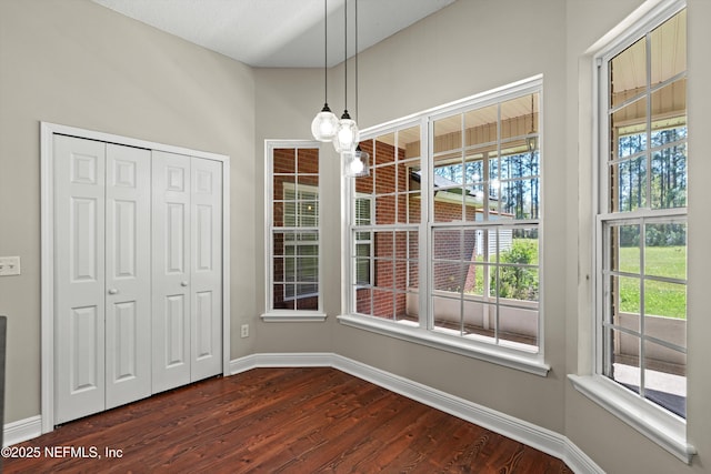 unfurnished dining area featuring dark wood finished floors and baseboards