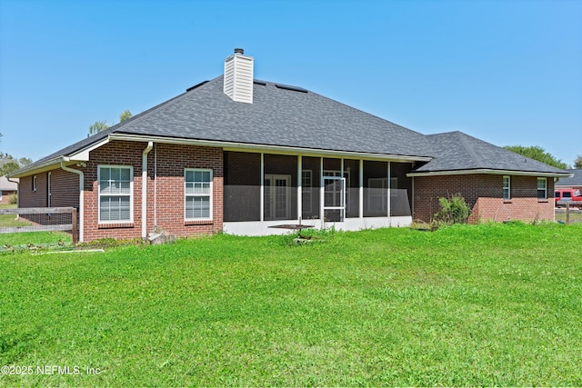 rear view of property with a lawn, brick siding, a sunroom, and a chimney
