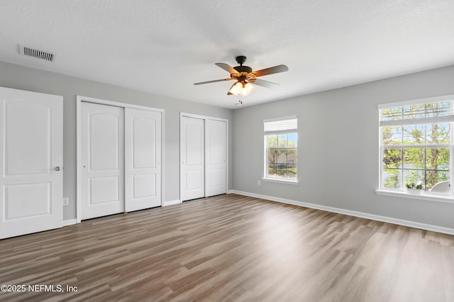 210 Crown Wheel Cir, Saint Johns, FL 32259 - unfurnished bedroom with two closets, wood finished floors, a textured ceiling, and ceiling fan