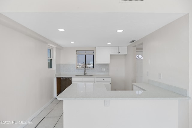 731 1st St S Unit 418, Jacksonville Beach, FL 32250 - kitchen featuring light tile patterned floors, backsplash, a sink, white cabinets, and a peninsula