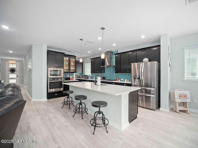 812 Windley Dr, Saint Augustine, FL 32092 - kitchen with wood tiled floor, a kitchen breakfast bar, light countertops, wall chimney exhaust hood, and appliances with stainless steel finishes