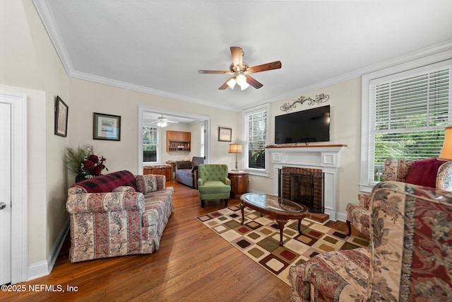 living room featuring a fireplace, ornamental molding, wood finished floors, and a ceiling fan