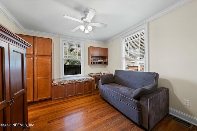 living area with ornamental molding, visible vents, a ceiling fan, and dark wood finished floors