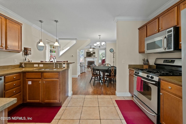 kitchen featuring light tile patterned flooring, ornamental molding, brown cabinets, appliances with stainless steel finishes, and a sink