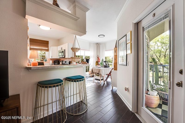 10961 Burnt Mill Rd Unit 321, Jacksonville, FL 32256 - kitchen featuring dark wood-style flooring, stainless steel microwave, white cabinetry, and a wealth of natural light