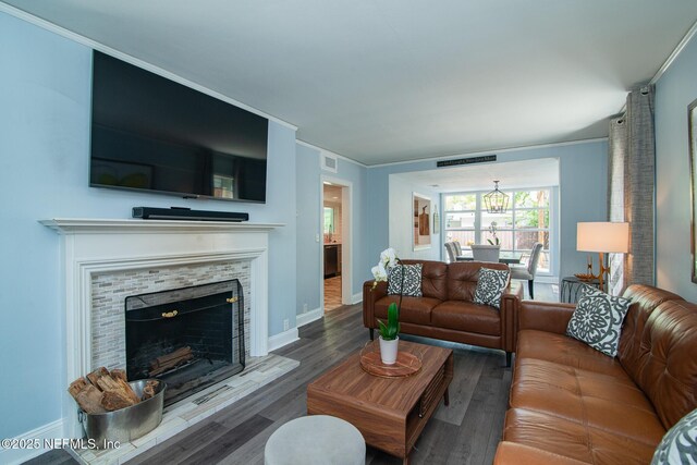 4245 Davinci Ave, Jacksonville, FL 32210 - living room with crown molding, a chandelier, wood finished floors, a tiled fireplace, and baseboards