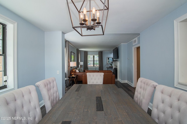 4245 Davinci Ave, Jacksonville, FL 32210 - dining space featuring a fireplace, visible vents, an inviting chandelier, and wood finished floors
