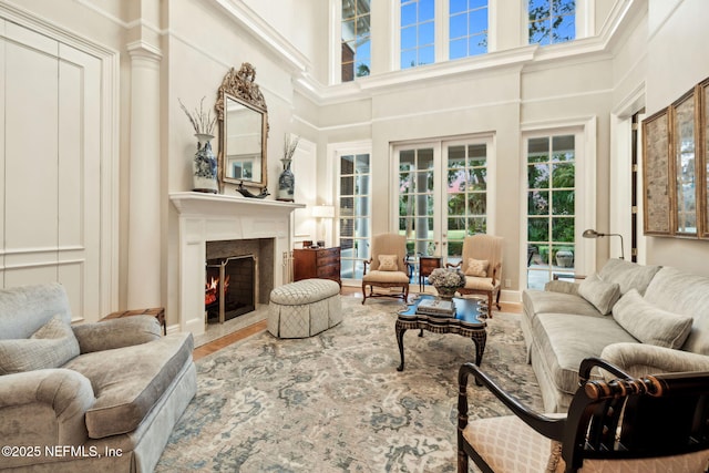 living area with wood finished floors, a high ceiling, and a lit fireplace