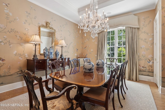 dining room with crown molding, baseboards, light wood finished floors, a notable chandelier, and a tray ceiling