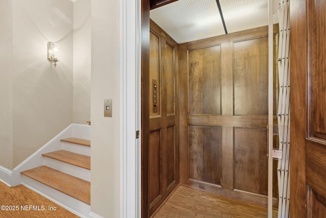 interior space featuring baseboards, elevator, and wood finished floors