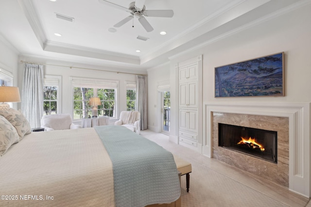 bedroom featuring access to exterior, a high end fireplace, visible vents, ornamental molding, and a tray ceiling