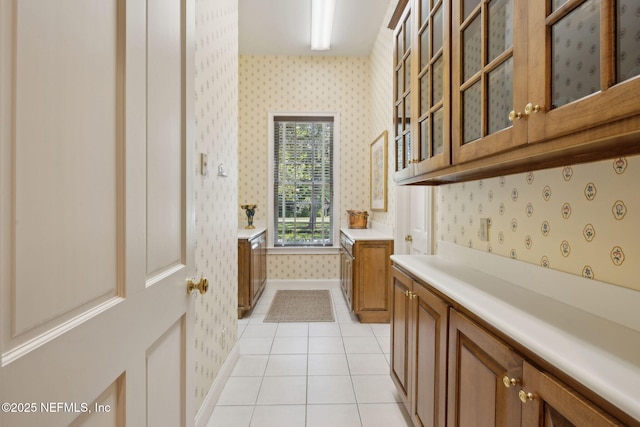 interior space featuring baseboards, wallpapered walls, and light tile patterned floors