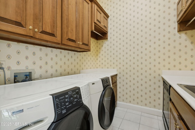 washroom featuring cabinet space, light tile patterned flooring, baseboards, wallpapered walls, and washer and clothes dryer