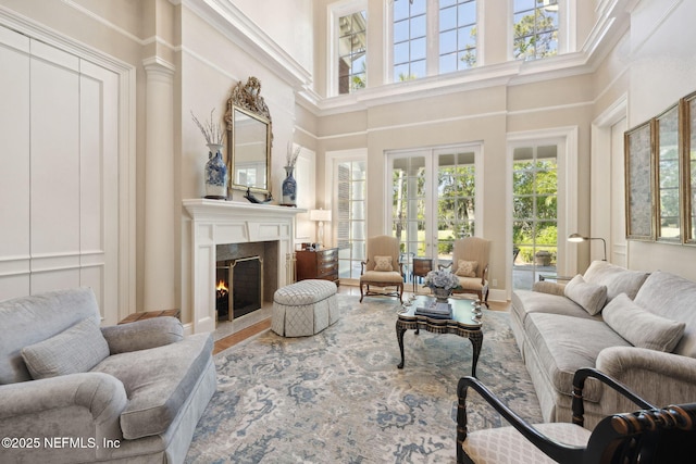 living room featuring a fireplace with flush hearth, a towering ceiling, and wood finished floors