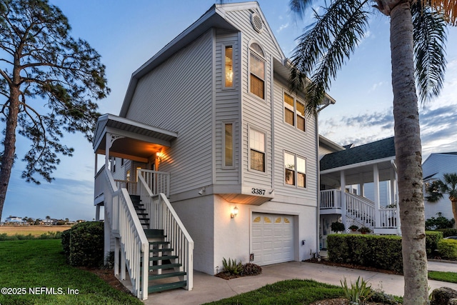 3387 Lighthouse Point Ln, Jacksonville, FL 32250 - view of home's exterior featuring a porch, a garage, stairs, stucco siding, and driveway