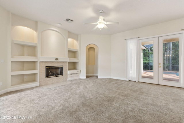 86183 Hampton Bays Dr, Fernandina Beach, FL 32034 - unfurnished living room featuring built in features, carpet floors, french doors, ceiling fan, and a fireplace
