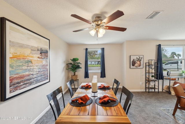 carpeted dining area with baseboards, visible vents, and a ceiling fan