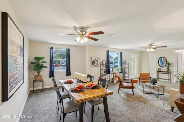 carpeted dining space featuring a ceiling fan, a textured ceiling, baseboards, and visible vents