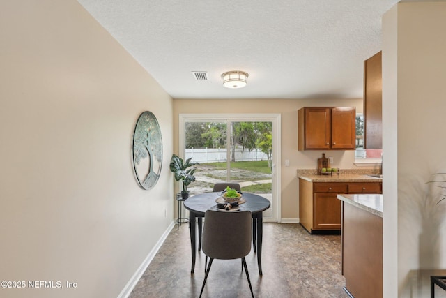 dining room with a textured ceiling, baseboards, and visible vents