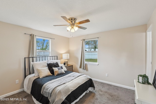carpeted bedroom with a ceiling fan, baseboards, and multiple windows