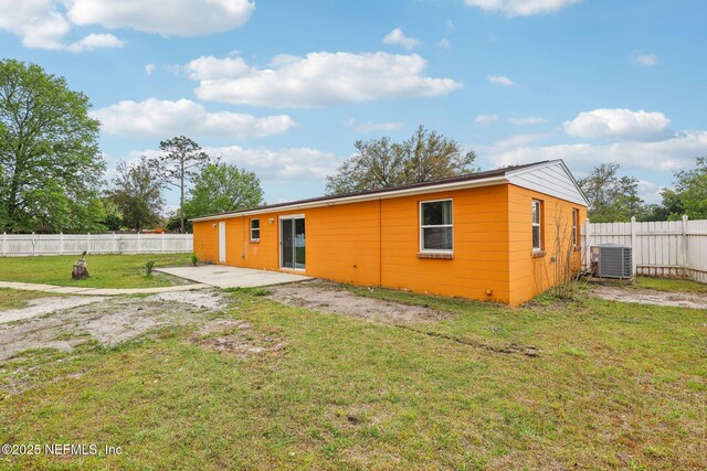 back of property with concrete block siding, a fenced backyard, a patio, and a lawn