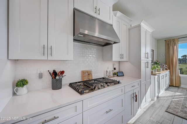 598 Marquesa Cir, Saint Johns, FL 32259 - kitchen featuring stainless steel gas cooktop, tasteful backsplash, light stone countertops, under cabinet range hood, and white cabinets