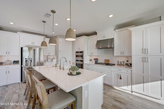 598 Marquesa Cir, Saint Johns, FL 32259 - kitchen with white cabinets, a breakfast bar, appliances with stainless steel finishes, under cabinet range hood, and light wood-type flooring