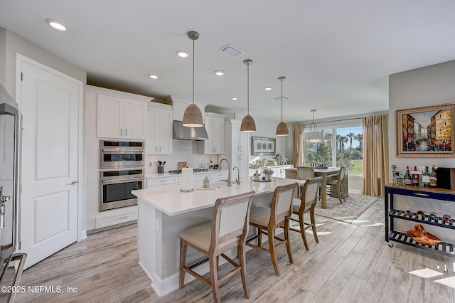 598 Marquesa Cir, Saint Johns, FL 32259 - kitchen featuring a breakfast bar area, appliances with stainless steel finishes, light wood-type flooring, visible vents, and white cabinets