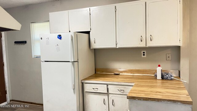 719 Broxton St, Jacksonville, FL 32208 - kitchen featuring white cabinetry, a textured ceiling, butcher block counters, freestanding refrigerator, and ventilation hood