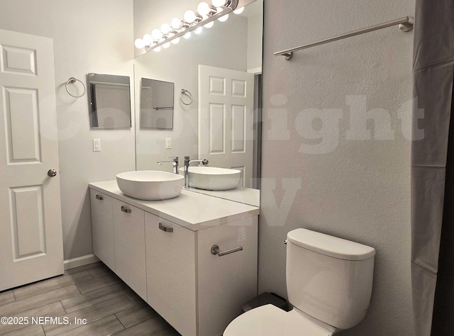 bathroom featuring vanity, toilet, and wood finished floors