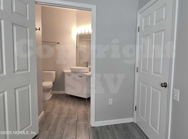 bathroom featuring toilet, baseboards, wood finish floors, and vanity