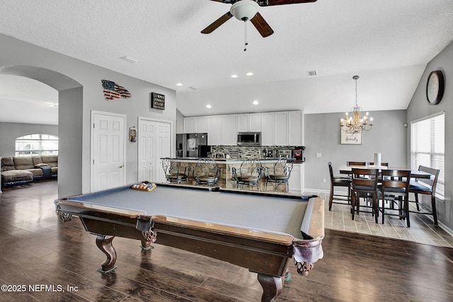 game room with a wealth of natural light, vaulted ceiling, wood finished floors, ceiling fan with notable chandelier, and arched walkways