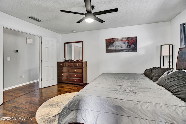 bedroom with baseboards, a textured ceiling, visible vents, and wood finished floors