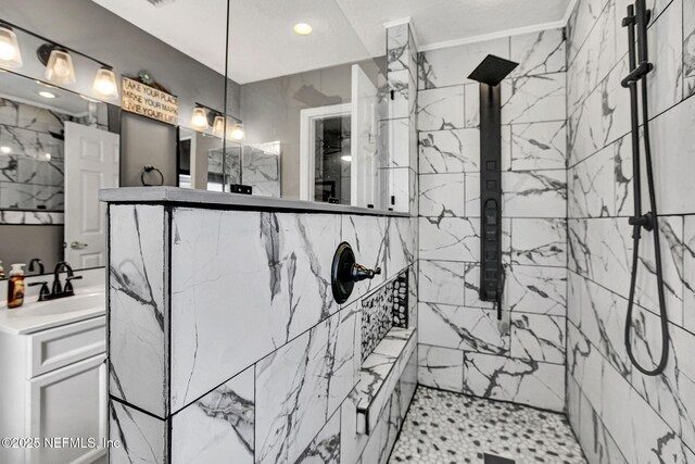 full bath with a marble finish shower and vanity